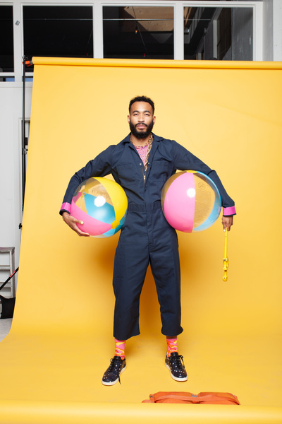 A person holding two giant beach balls and one small.