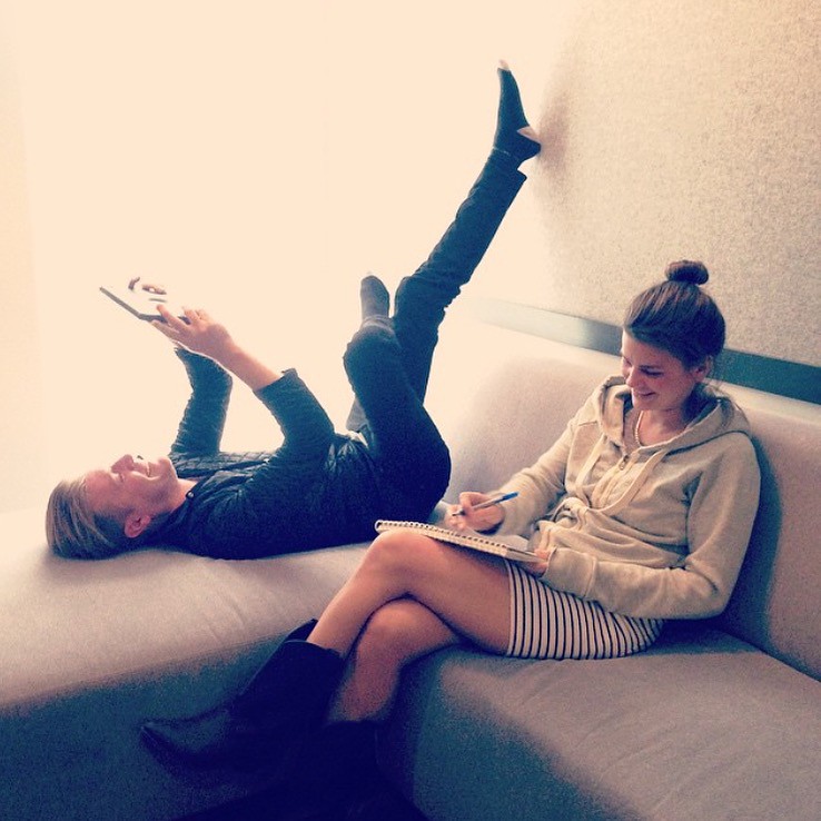 Couple sitting on couch with laptop and paper notebook.